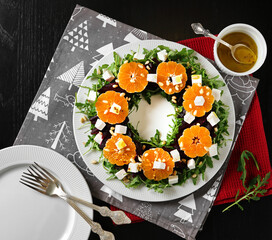 Christmas appetizer. Christmas wreath salad with beetroot, tangerines, feta cheese and arugula on the black table. View from above.