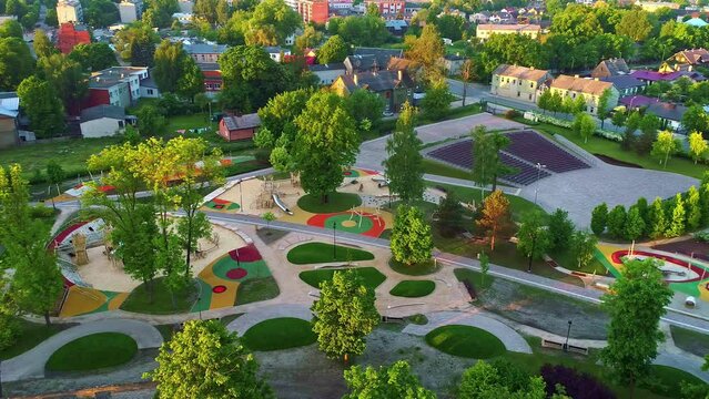 Aerial shot of a vibrant community park with playgrounds and lush greenery during sunset