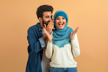 Delighted arab muslim couple sharing joyful secret, man whispering into woman's ear - obrazy, fototapety, plakaty