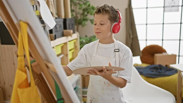 Adorable little blond boy artist confidently dancing to the music he's listening to while drawing in our fun-filled art studio