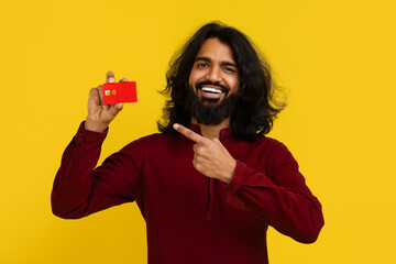 Happy bearded indian guy hipster showing bank credit card