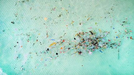 Aerial view of ocean pollution, depicting a swath of colorful plastic debris contaminating turquoise sea waters, highlighting environmental concerns