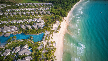 Aerial view of a luxury beachfront resort with tropical palm trees and an inviting blue swimming...