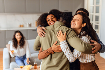 Group of diverse friends sharing hug during home party gathering - obrazy, fototapety, plakaty