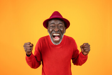 Cheerful excited old black man in hat, with open mouth, scream, rise fists, celebrate win