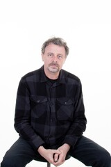 Handsome man with beard in canadian plaid shirt checked lumberjack sit isolated on white background