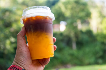 A cold brew espresso with fresh orange juice in takeaway cup, it showing the texture of two layer...