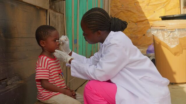 doctor nurse in africa collecting a swab sample to a black African children eyes , healthcare prevention system in Africa 