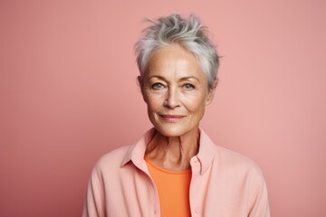 Portrait of smiling senior woman with short gray hair on pink background