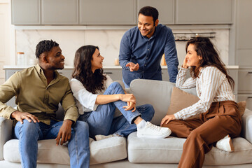 group of four diverse students talking sitting in living room - obrazy, fototapety, plakaty