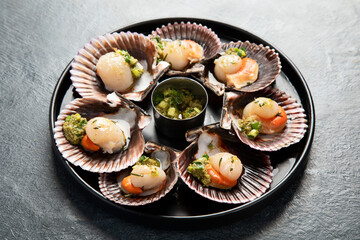 Fried scallops with butter and green sauce served in seashells.