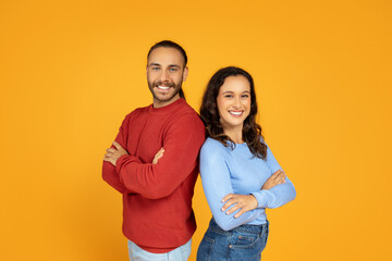 Confident young man and woman standing back to back