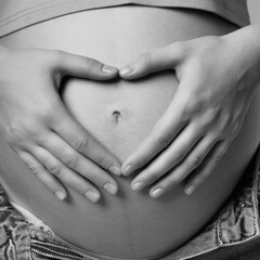Black and white photo of  female on 6th month of pregnancy. Woman touching with hands her naked...
