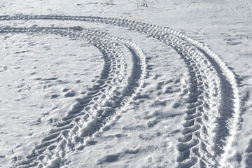 Traces of a wheeled tractor in the snow. Winter snow patterns