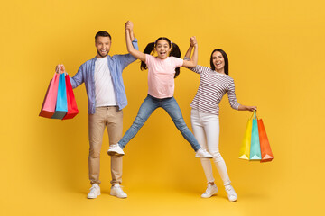 Naklejka premium Seasonal Sales Concept. Happy Family Of Three Jumping With Shopping Bags