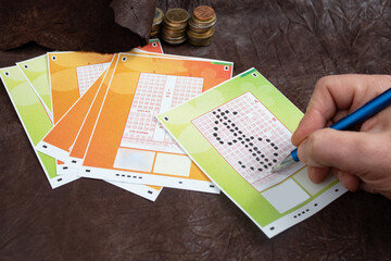 Male hand choosing numbers on a lottery ticket, in form of dollar  currency symbol, on genuine...