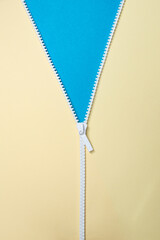 White zipper opening beige background to reveal blue bright color, abstract creative backdrop