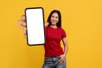 Positive young asian woman showing phone with mockup - obrazy, fototapety, plakaty