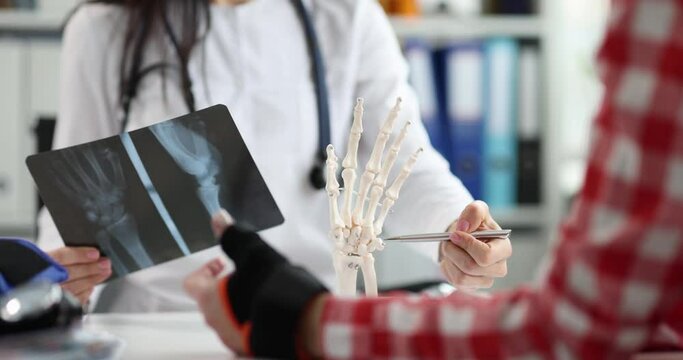 Orthopedist shows x-ray anatomy of hand and patient in clinic. Hand injury concept