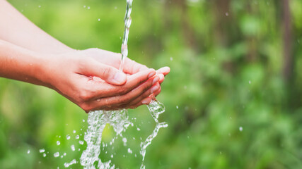 water pouring flow on woman hand on nature background
