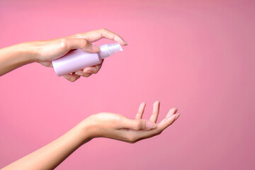 Woman holding spray sanitizer bottle mockup over pink background