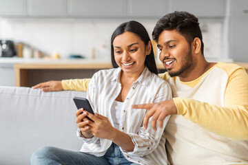 Happy Young Indian Couple Using Mobile Phone Together At Home