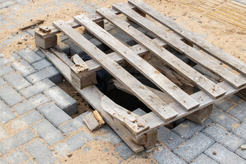 Hole in asphalt is covered with wooden pallet