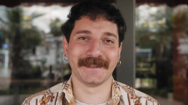 Portrait of handsome hispanic stylish young guy looking to camera. Close up face of millennial man smiling outdoors.