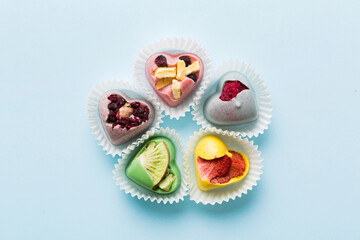 chocolate sweets in the form of a heart with fruits and nuts on a colored background. top view with space for text, holiday concept