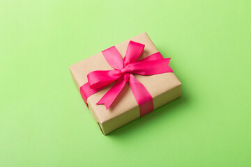 Wrapped christmas or other holiday handmade present in craft paper with colored ribbon. Present box, decoration of gift on table, top view with copy space