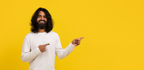 Positive hindu guy pointing at copy space for advertisement