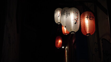 An alley, at night, illuminated by hanging red Chinese lanterns