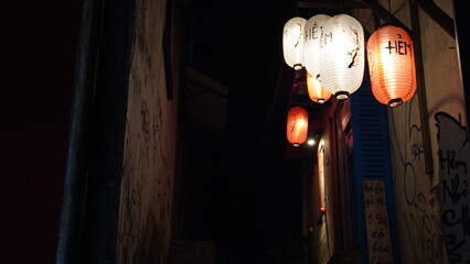 An alley, at night, illuminated by hanging red Chinese lanterns