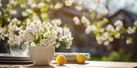 Fotobehang A table with cups and flowers on it Cup of tea with white apple blossoms Wooden texture table top on blurred white rustic kitchen interior Template for product display with flowers and fruit. © khatija