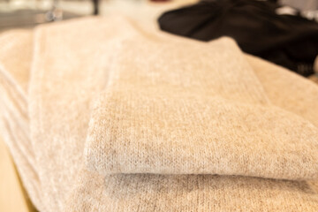 selective focus, white wool sweater folded on a clothing store rack