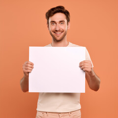 A handsome man, a model for advertising, holds a blank placard in his hands. empty space for editing and ads.