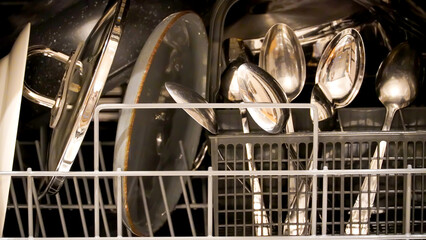 Close-up of plates, pots and spoons inside the dishwasher