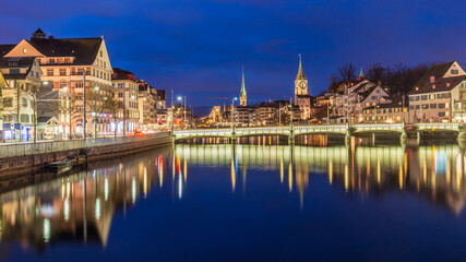 Fototapeta na wymiar Night cityscape with Limmat river of the historical Zurich city, Switzerland.Panoramic view of historic Zurich city center with famous Fraumunster Church and river Limmat at Lake Zurich ,in twilight.
