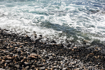 Rocky shore background. Volcanic rock on ocean shore. Tenerife on Canary island texture. Sea wave...