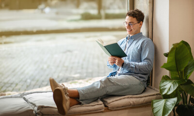 Focused calm smart european young man student in glasses read book, enjoy peace - obrazy, fototapety, plakaty