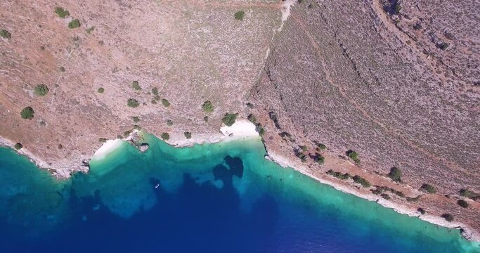 Overhead retreating drone shot of Agriosiko, an isolated beach off the coast of the island of Kefalonia, Greece.