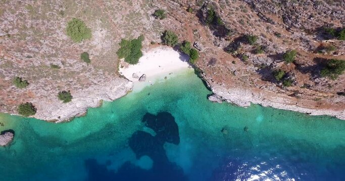 Overhead retreating drone shot of the coastline of Agriosiko Beach a secret getaway in Kefalonia, situated in the Ionian islands off the coast of Greece.