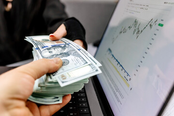 Money in the hands of an accountant or bank employee, transfer of money, financial market. Money on the background of a financial chart. Business, loans, deposits, payments and accounting.