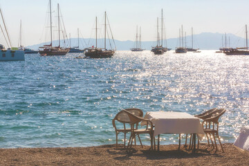 Bodrum, Turkey. Table with chairs from a restaurant on the beach with a sea view and ships
