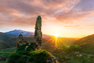 immersive landscape of old castle ruins on foreground and beautiful mountains with sunset with...
