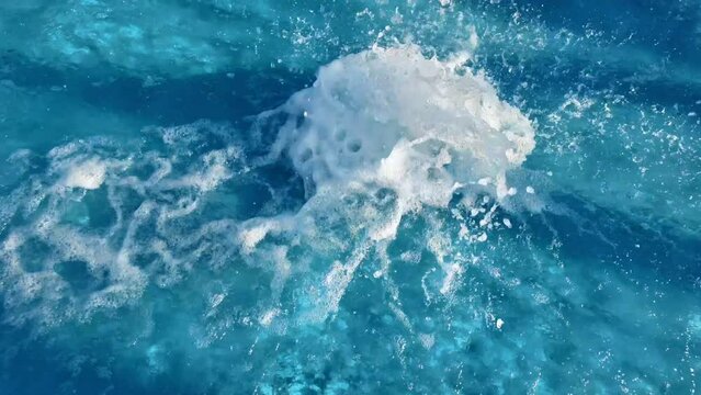 Turquoise ocean waters with white foam, possibly from a boat wake or wave, emphasizing the beauty of natural sea textures