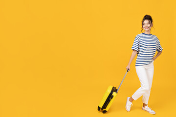 A young girl with a yellow suitcase on a yellow background