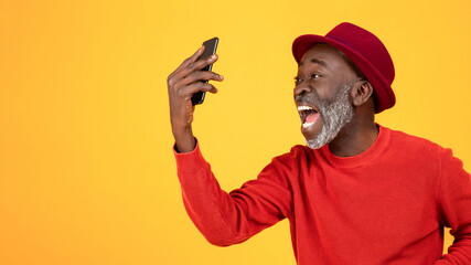 Happy or angry excited senior african american man in hat and red clothes