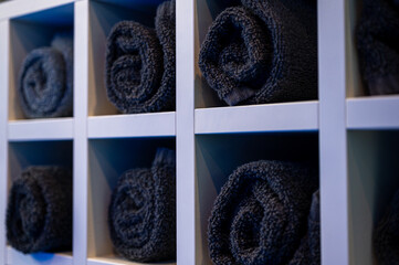 twisted folded towels dark terry on light shelf, side view, for face or head in barbershop