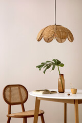 The stylish dining room with round table, rattan chair, lamp and kitchen accessories. Leaf in a...
